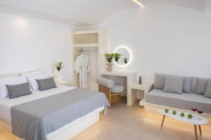 a white bedroom with a bed and a couch at Theophrasti Suites in Foinikiá
