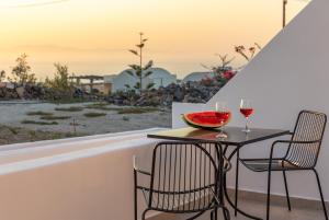 a table with two glasses of wine and a bowl of watermelon at Theophrasti Suites in Foinikiá