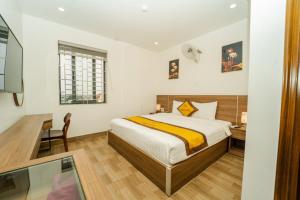 a bedroom with a bed and a desk and a window at Sonne Hotel Quang Binh in Ðộng Hỏi
