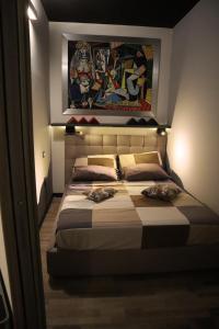 Un dormitorio con una cama grande con una pintura encima. en Orticello Appartment en San Sperate