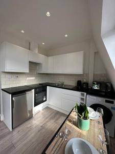 een keuken met witte kasten en een tafel met wijnglazen bij Modern flat in Victoria in Londen