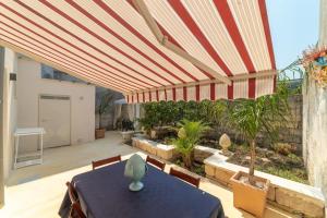 un patio con una mesa y una sombrilla grande en Il colore del Salento, en Carpignano Salentino