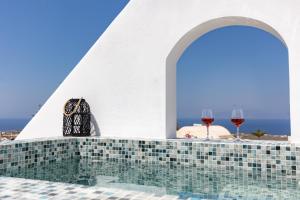 a swimming pool with two glasses of wine at Theophrasti Suites in Foinikiá