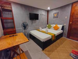 a room with a bed with a tv and a table at RL Harbor Inn in El Nido