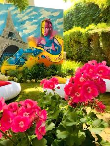 a painting of a woman in a car in a park with pink flowers at Kyriad Paris Saint Ouen in Saint-Ouen