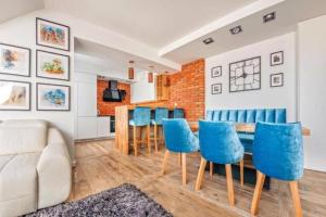 a living room with a dining room table and blue chairs at Golden Apartments Gdansk&SwB12 in Gdańsk