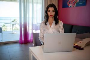 una donna seduta a un tavolo con un computer portatile di Valentino Resort a Grottammare