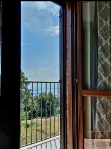 ventana con vistas a un balcón con árboles en Casa Vacanze La Perla del Lago en Passignano sul Trasimeno