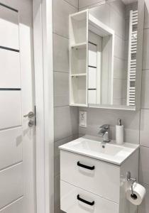 a white bathroom with a sink and a mirror at Golden Apartments Gdansk&P29 in Gdańsk