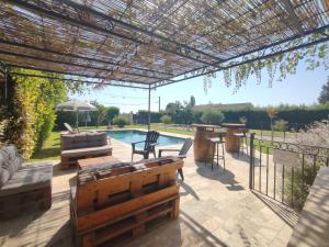 un patio esterno con pergolato e piscina di Villa moderne dans la tranquillité de la campagne a Caderousse