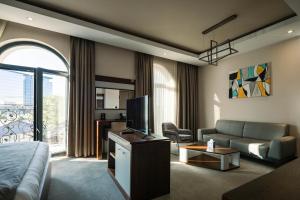 a living room with a couch and a tv in a room at Hotel Prishtina in Prishtinë