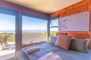 Un dormitorio con una cama y una ventana grande. en Upmarket, Spacious and Stunning Sea Views, en Cape St. Francis