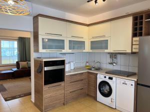 a kitchen with white cabinets and a washer and dryer at Zubci mountain apartment in Bar