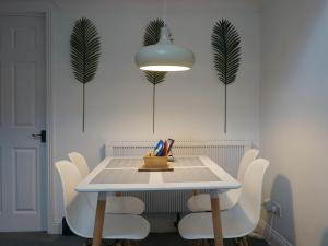 a dining room table with white chairs and a light fixture at Westgate Garden riverside in Canterbury