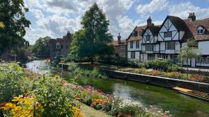 une rivière dans un village avec des maisons et des fleurs dans l'établissement Westgate Garden riverside, à Canterbury
