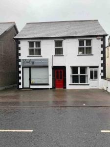 a white building with a red door on a street at Newly refurbished village flat in Cullybackey