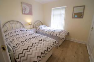 a bedroom with two beds and a window at Newly refurbished village flat in Cullybackey