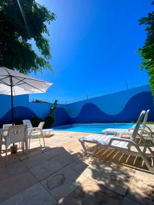 福塔萊薩的住宿－Marbello Ariau Hotel，一组椅子和一把遮阳伞,位于游泳池旁