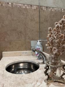 un lavandino del bagno con un vaso di fiori accanto di Luminoso departamento céntrico a Corrientes Altre 20 foto