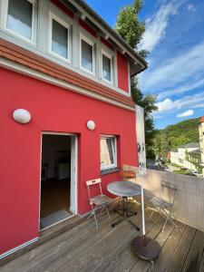 a red house with a table and chairs on a deck at Turmwohnung in Kreischa