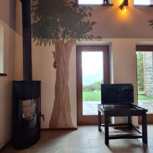 a living room with a fireplace and a tree on the wall at Baita Bihj - Villaggio dei Crodini in Crodo