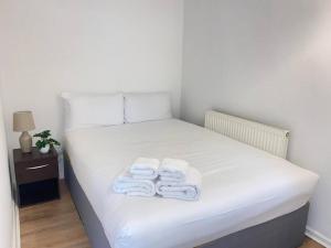 a white bed with towels on it with a night stand at Stylish & Tranquil Flat with Excellent Connections in London