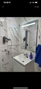ein weißes Badezimmer mit einem Waschbecken und einem Spiegel in der Unterkunft Encantador apartamento recién reformado a estrenar in Laredo