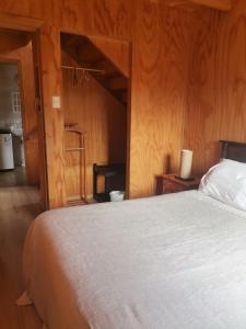 a bedroom with a bed and a wooden wall at Cabaña Rossbach Puyuhuapi in Puerto Puyuhuapi