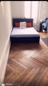 a bed sitting on top of a wooden floor at Location chambre long et court séjour in Saint-Étienne