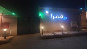 Qarār的住宿－شاليهات قمرا，夜间建筑物一侧的标志