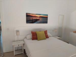 a white bedroom with a bed and a painting on the wall at Casa Oliva 52 in Seville