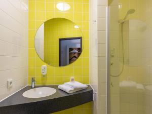 a bathroom with a sink and a mirror and a shower at B&B Hotel Mülheim an der Ruhr in Mülheim an der Ruhr