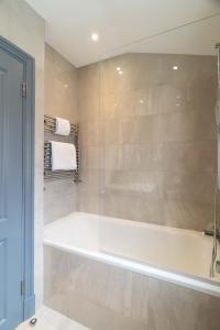 uma casa de banho com uma banheira e um chuveiro em vidro. em Margravine Gardens by Viridian Apartments em Londres