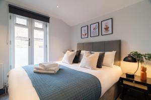 a bedroom with a large bed with a blue blanket at Margravine Gardens by Viridian Apartments in London