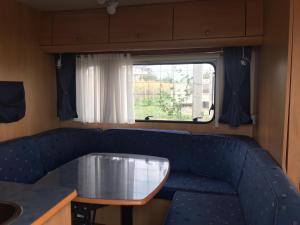 a blue couch with a table in front of a window at Agri Camping italiano - Eucalyptus in Shënkoll