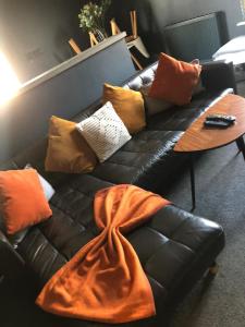 a black leather couch with pillows and a table at Raby Apartment in Darlington