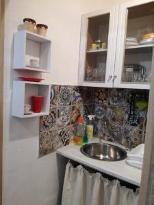 La cuisine est équipée d'un évier et d'une armoire blanche. dans l'établissement La Gorgone, à Casteldaccia