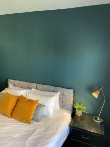 a bedroom with a blue wall and a bed with pillows at Raby Apartment in Darlington