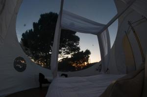 1 dormitorio con cama y ventana en una tienda de campaña en Burbujas Astronómicas Albarari Coruña, en Oleiros