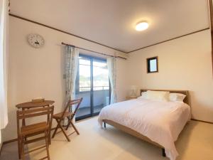 una camera da letto con un letto, un tavolo e una finestra di 浜町小院别馆 a Takamatsu
