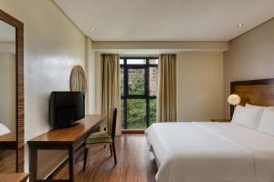 a hotel room with a bed and a desk with a television at Protea Hotel by Marriott Benin City Select Emotan in Benin City