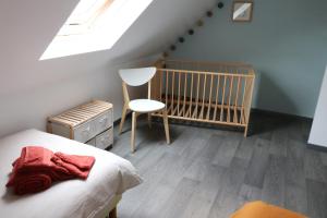 a bedroom with a crib and a chair in it at Maison avec terrasses à 300m de la mer Juno Beach in Bernières-sur-Mer