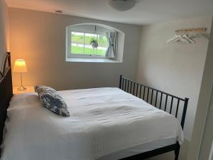 1 dormitorio con 1 cama blanca y ventana en Lilla Stenhuset, en Ystad