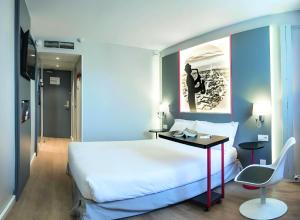 サン・トゥアンにあるKyriad Paris Saint Ouenのベッドルーム(白い大型ベッド1台、デスク付)