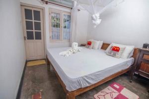 1 dormitorio con 1 cama con sábanas blancas y ventana en Village Headman's Five Bedrooms Entire Bungalow, en Bentota