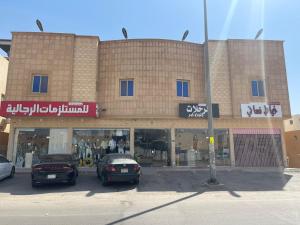 two cars parked in a parking lot in front of a store at Spacious Apartments at Basla St 3 mins from King Fahd Stadium in Riyadh