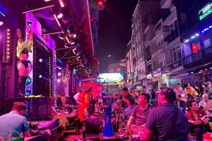 een menigte mensen die 's nachts op straat zitten bij Ha Vy Hotel in Ho Chi Minh-stad