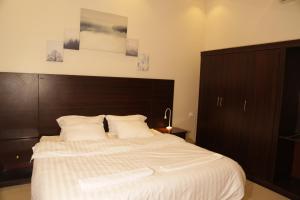 a bedroom with a large bed with a wooden headboard at Spacious Apartments at Basla St 3 mins from King Fahd Stadium in Riyadh