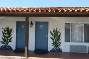 ein Haus mit zwei blauen Türen und Ananaspflanzen in der Unterkunft Sunset Motel in Santa Barbara