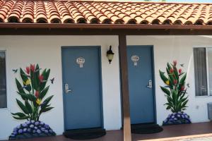 3 portes bleues sur le côté d'un bâtiment avec des plantes dans l'établissement Sunset Motel, à Santa Barbara